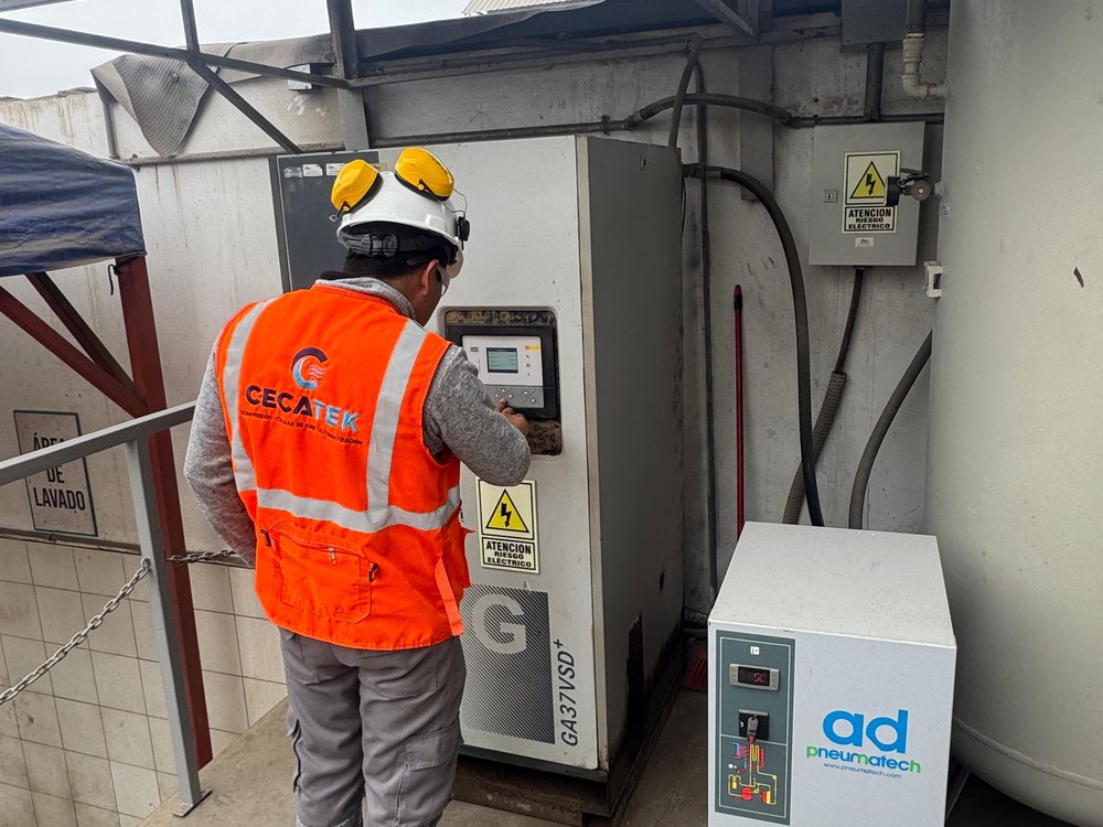 Técnico operando el panel de control de un compresor industrial